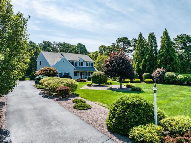 a front view of a house with a yard and trees
