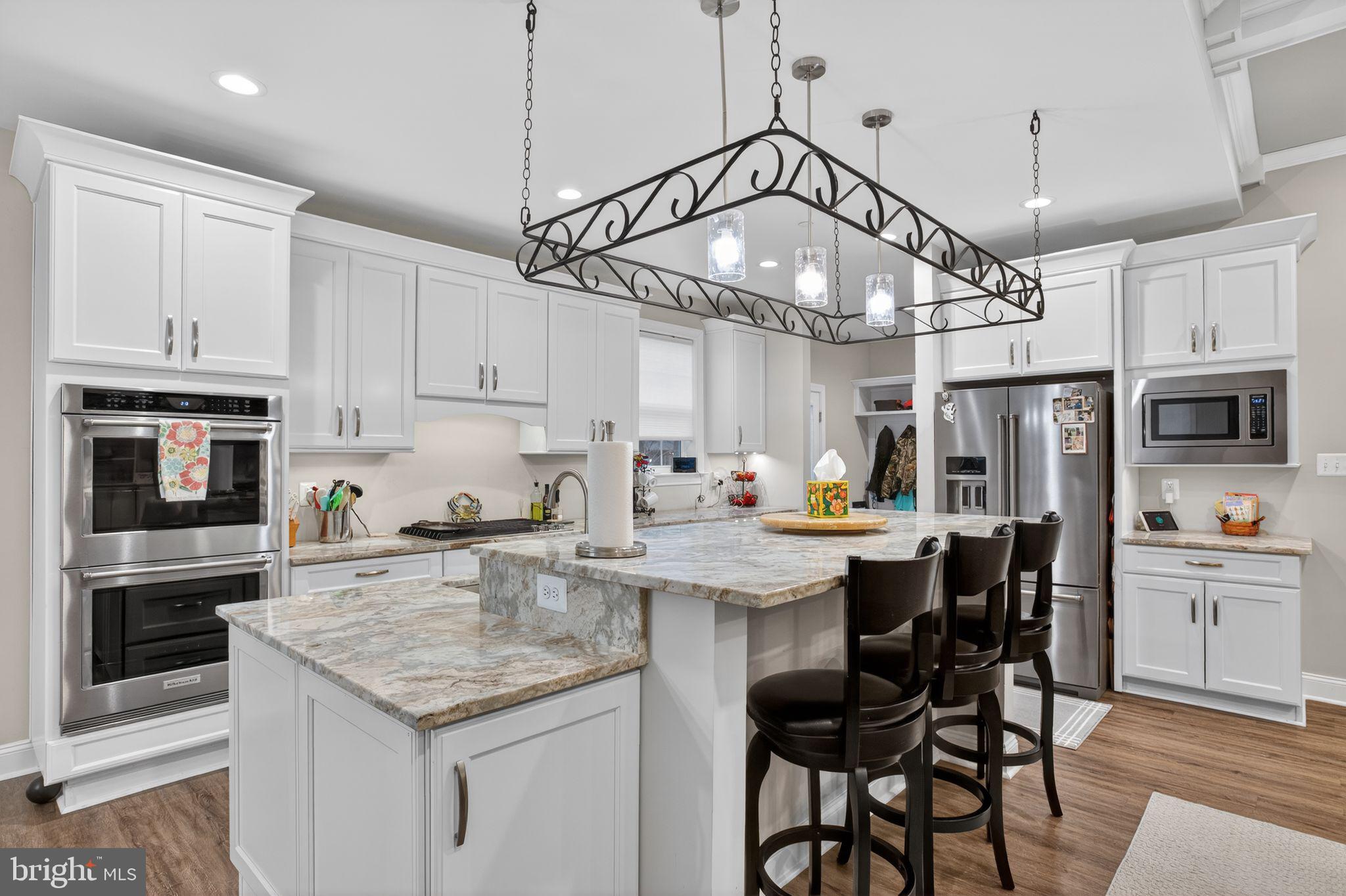 14730 Locust Court Swan Point, MD 20645 - Photo 15 of 38 a kitchen with stainless steel appliances kitchen island granite countertop a table chairs in it and wooden floors
