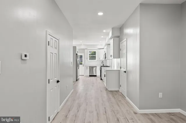 a view of a hallway with wooden floor and a bathroom