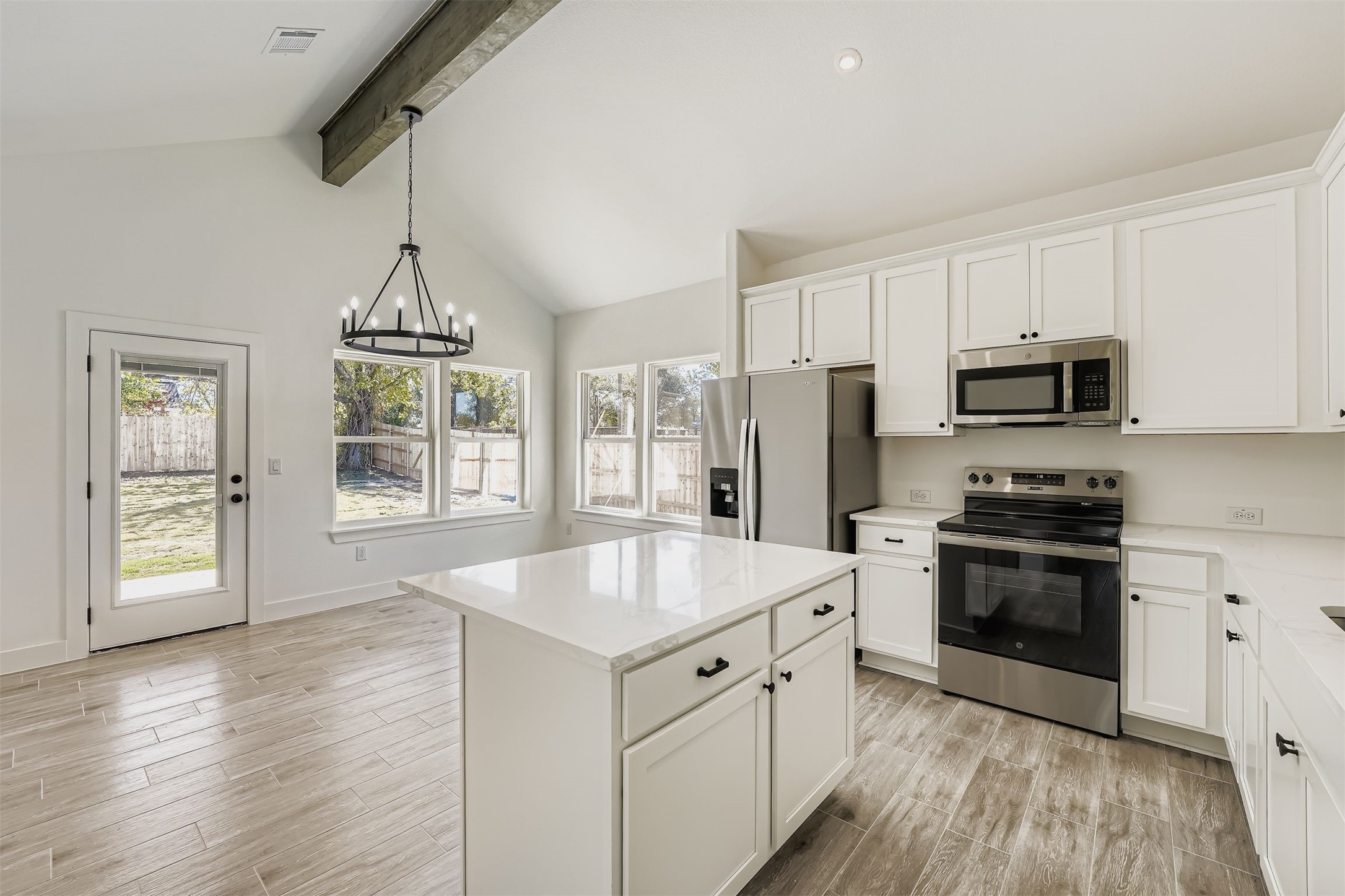 Open dining area with wood-style vinyl plank floors, a modern chandelier, and a clear view into the kitchen.