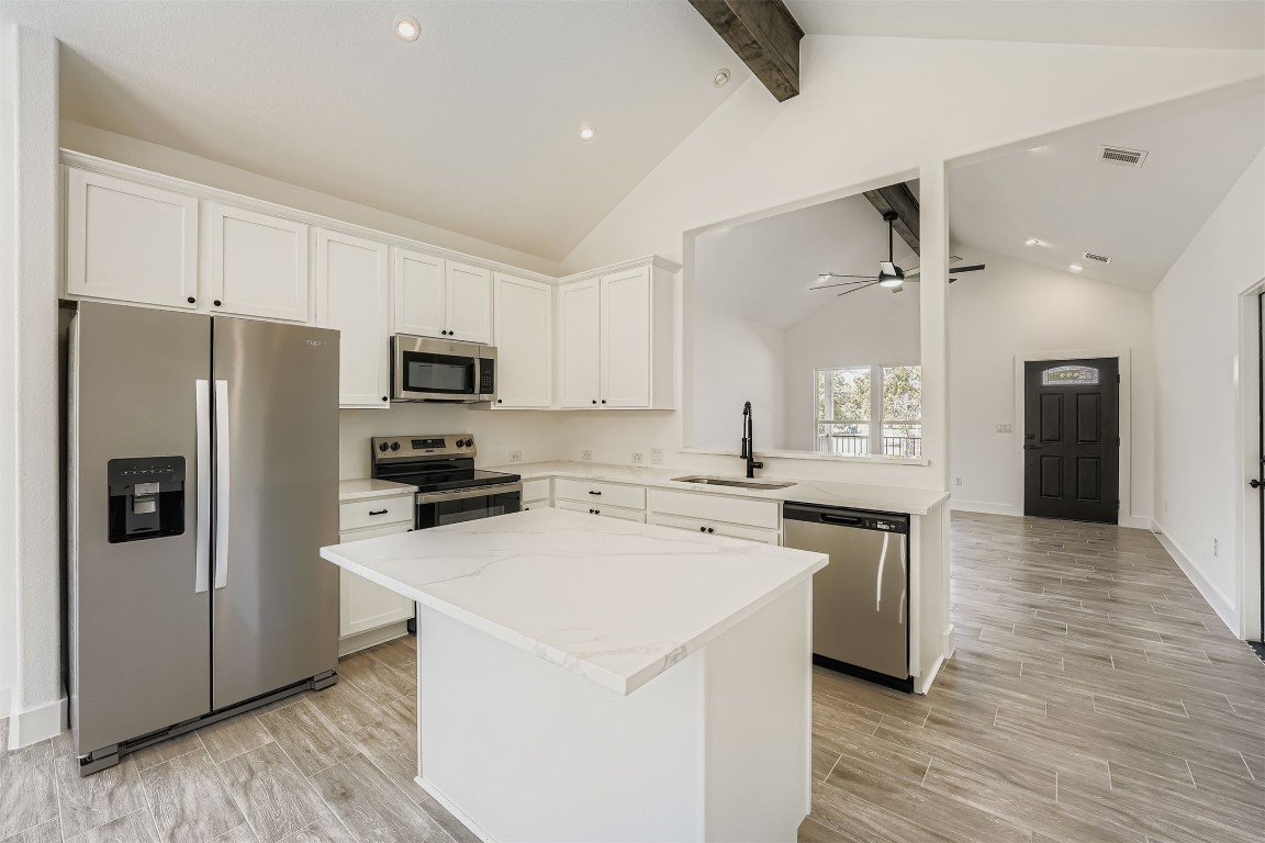 701 East 3rd Street Elgin, TX 78621 - Photo 11 of 28 Kitchen with stainless steel appliances, white cabinetry, a kitchen island, and beamed ceiling