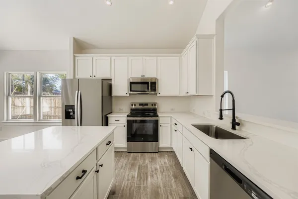 a kitchen with a refrigerator a sink a stove and cabinets