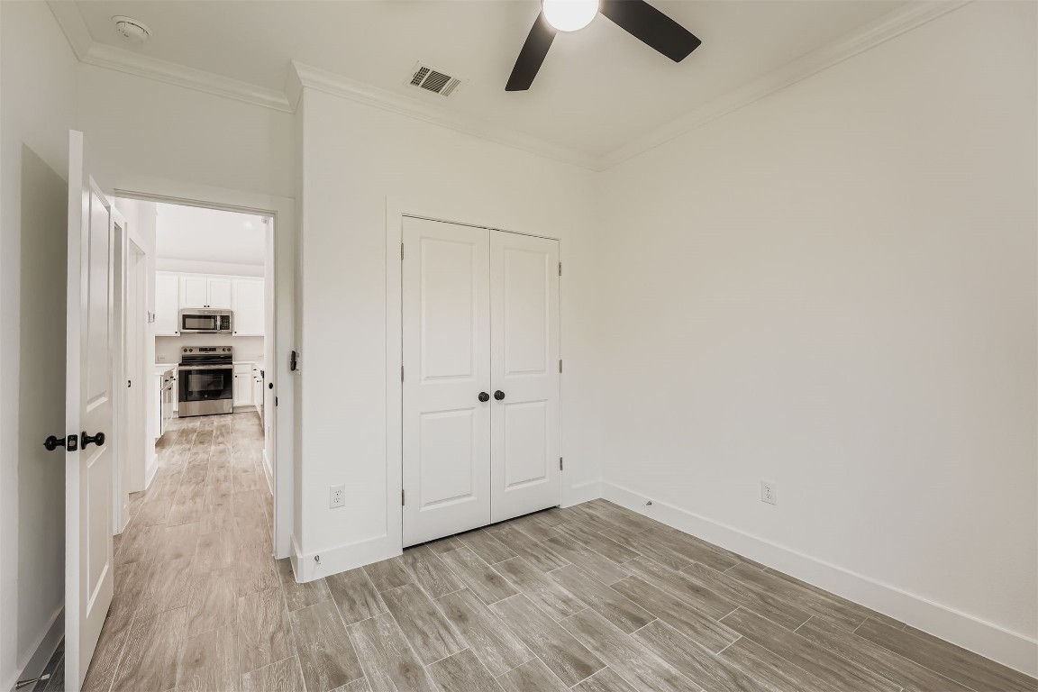 701 East 3rd Street Elgin, TX 78621 - Photo 18 of 28 Bedroom 2 featuring wood-style vinyl plank flooring, a closet and a view into the bright kitchen area