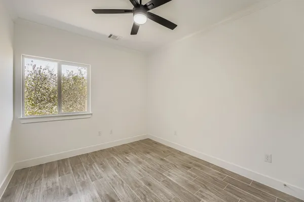 an empty room with a window and a ceiling fan