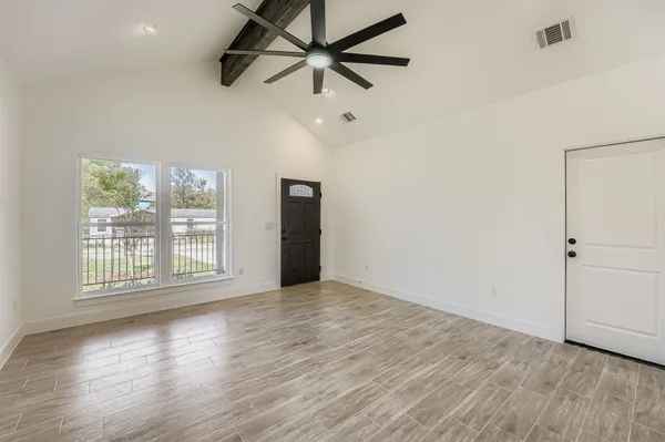 a view of an empty room with wooden floor and a window