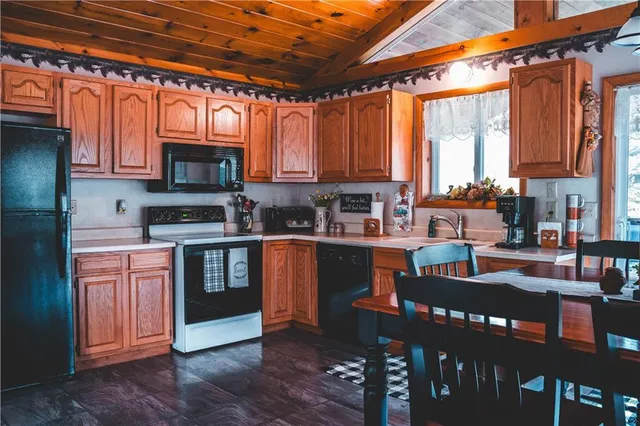 a kitchen with stainless steel appliances granite countertop a stove top oven a sink dishwasher a dining table and chairs with wooden floor