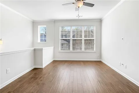 an empty room with wooden floor fan and windows
