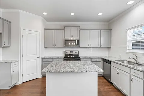 a kitchen with granite countertop white cabinets and stainless steel appliances