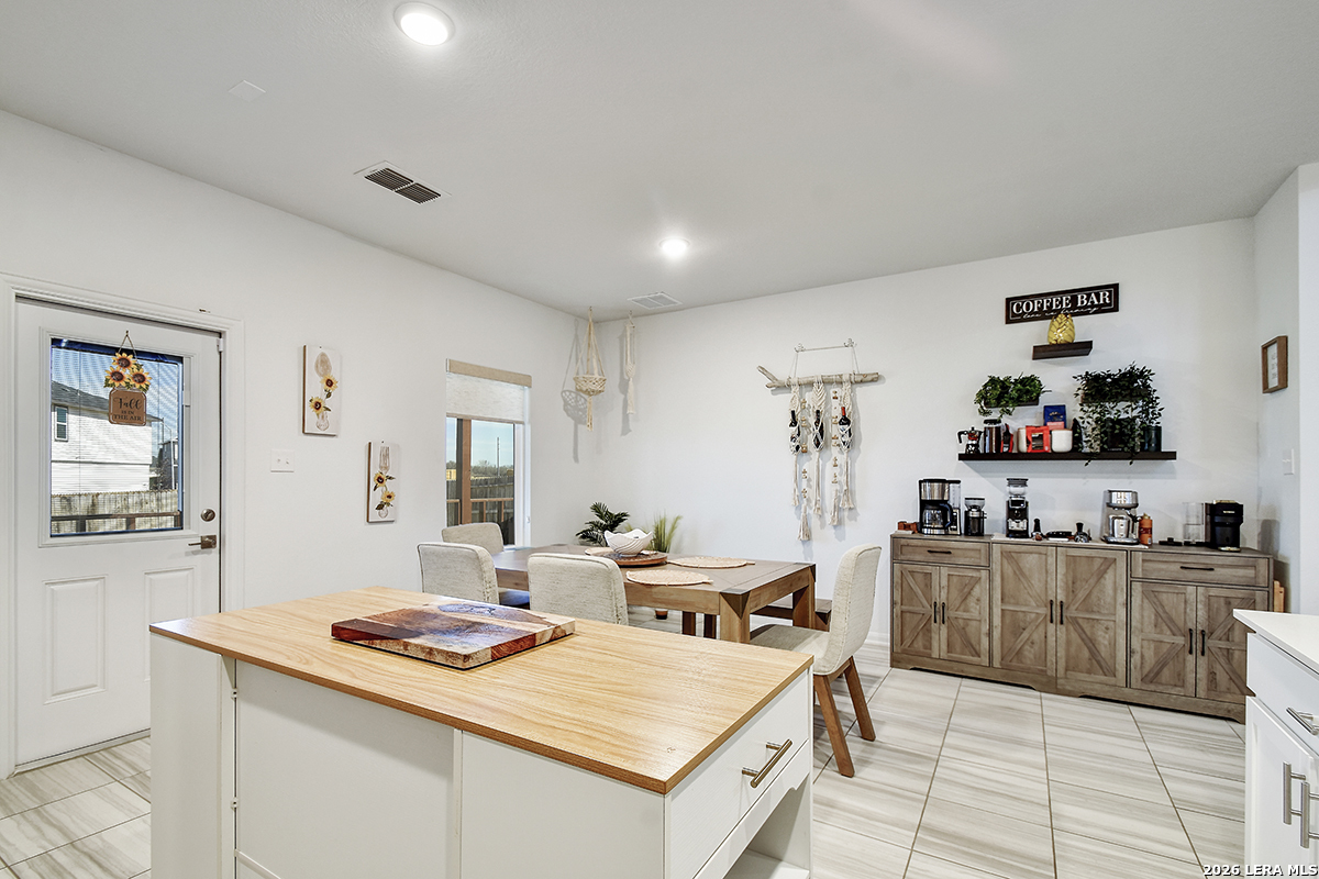 8863 Grey Elm Elmendorf, TX 78112 - Photo 13 of 35 a view of a kitchen with kitchen island a stove a refrigerator a sink dishwasher a dining table and chairs with wooden floor