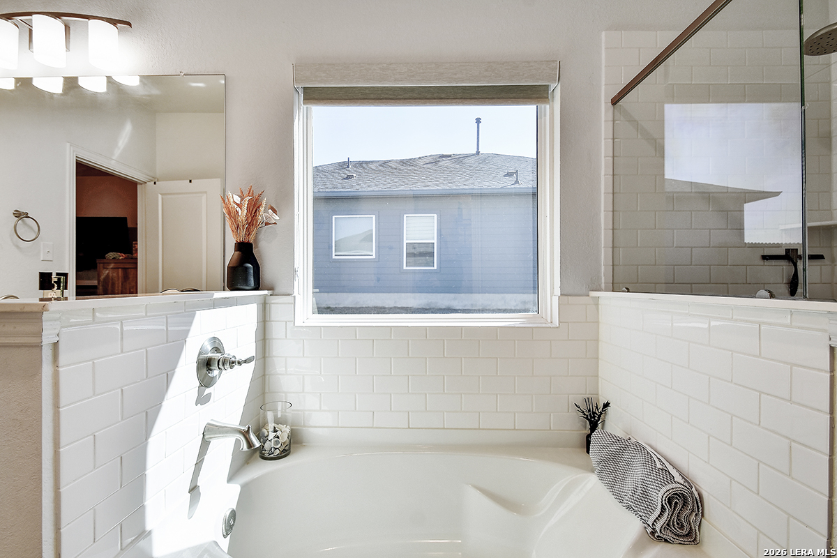 8863 Grey Elm Elmendorf, TX 78112 - Photo 22 of 35 a bathroom with a tub sink and mirror