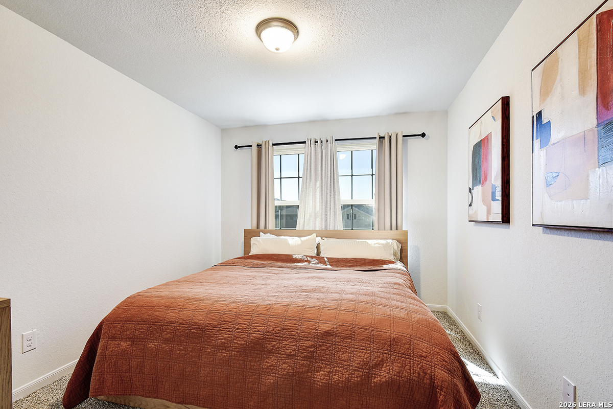 8863 Grey Elm Elmendorf, TX 78112 - Photo 27 of 35 a large bed sitting in a bedroom next to a window