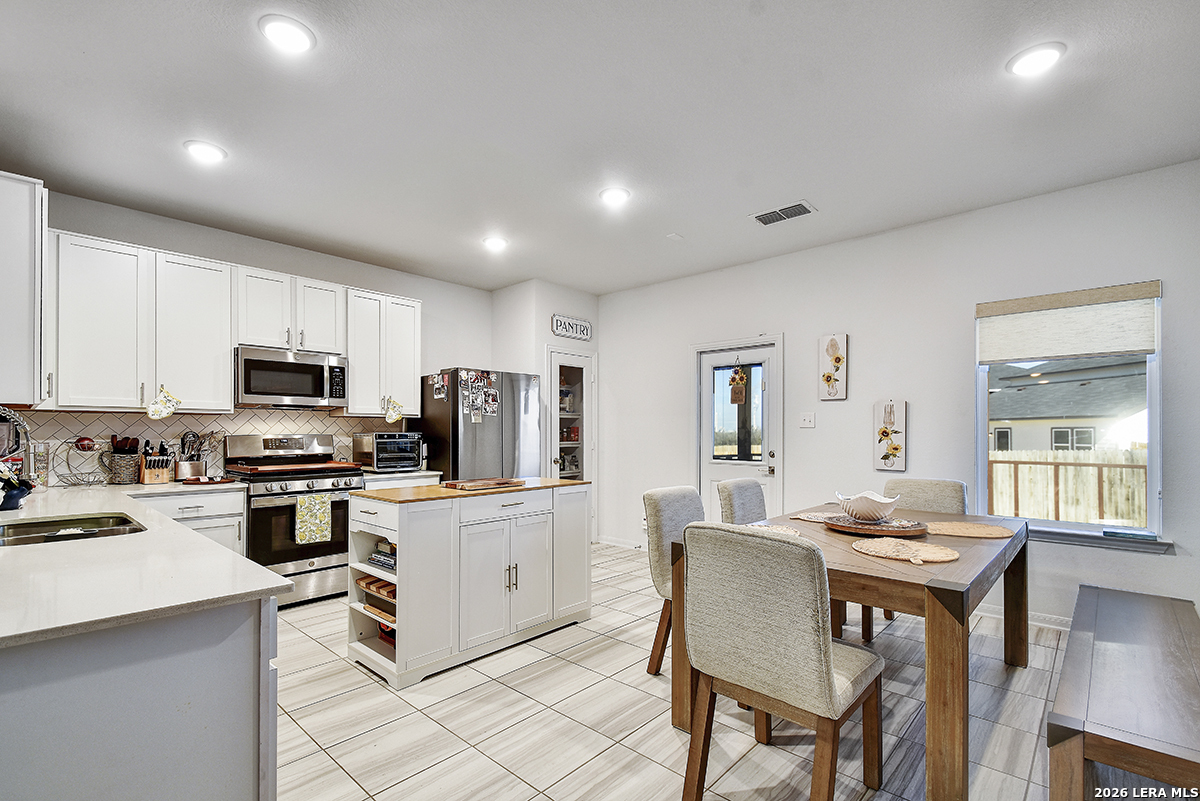 8863 Grey Elm Elmendorf, TX 78112 - Photo 9 of 35 a kitchen with a table chairs microwave and cabinets