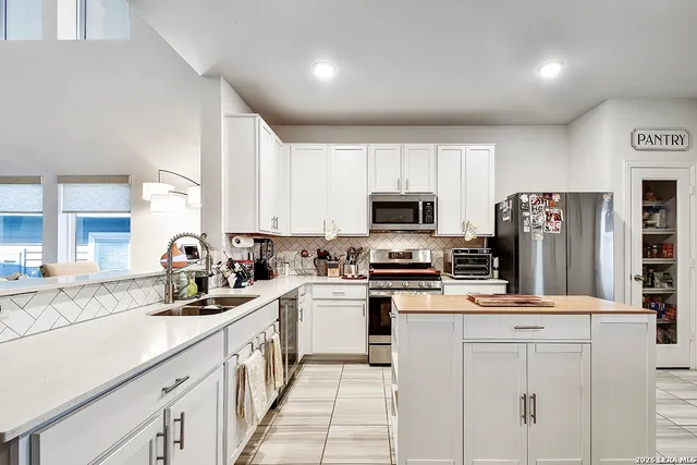 a kitchen with stainless steel appliances a white stove top oven a sink a refrigerator and white cabinets