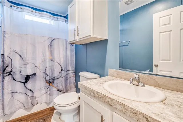 a bathroom with a granite countertop sink and a toilet