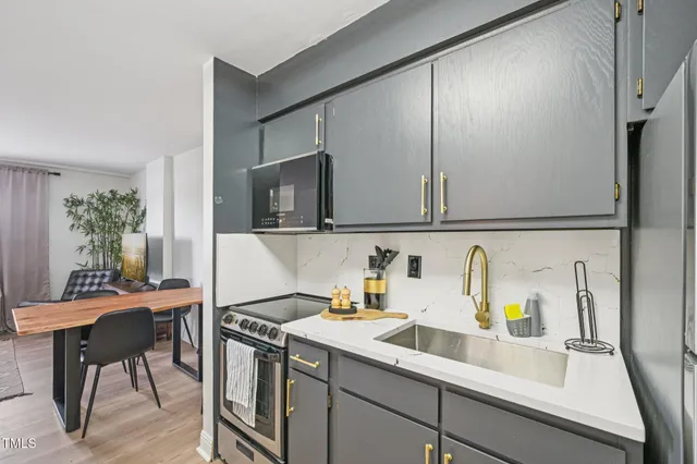 a kitchen with stainless steel appliances a sink a stove and a refrigerator with wooden floor