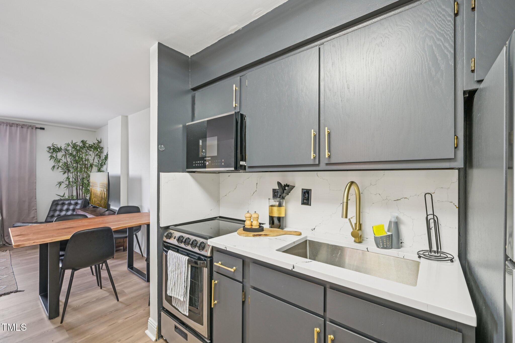 4700 Westgrove Street, Unit 721 Raleigh, NC 27606 - Photo 13 of 21 a kitchen with stainless steel appliances a sink a stove and a refrigerator with wooden floor