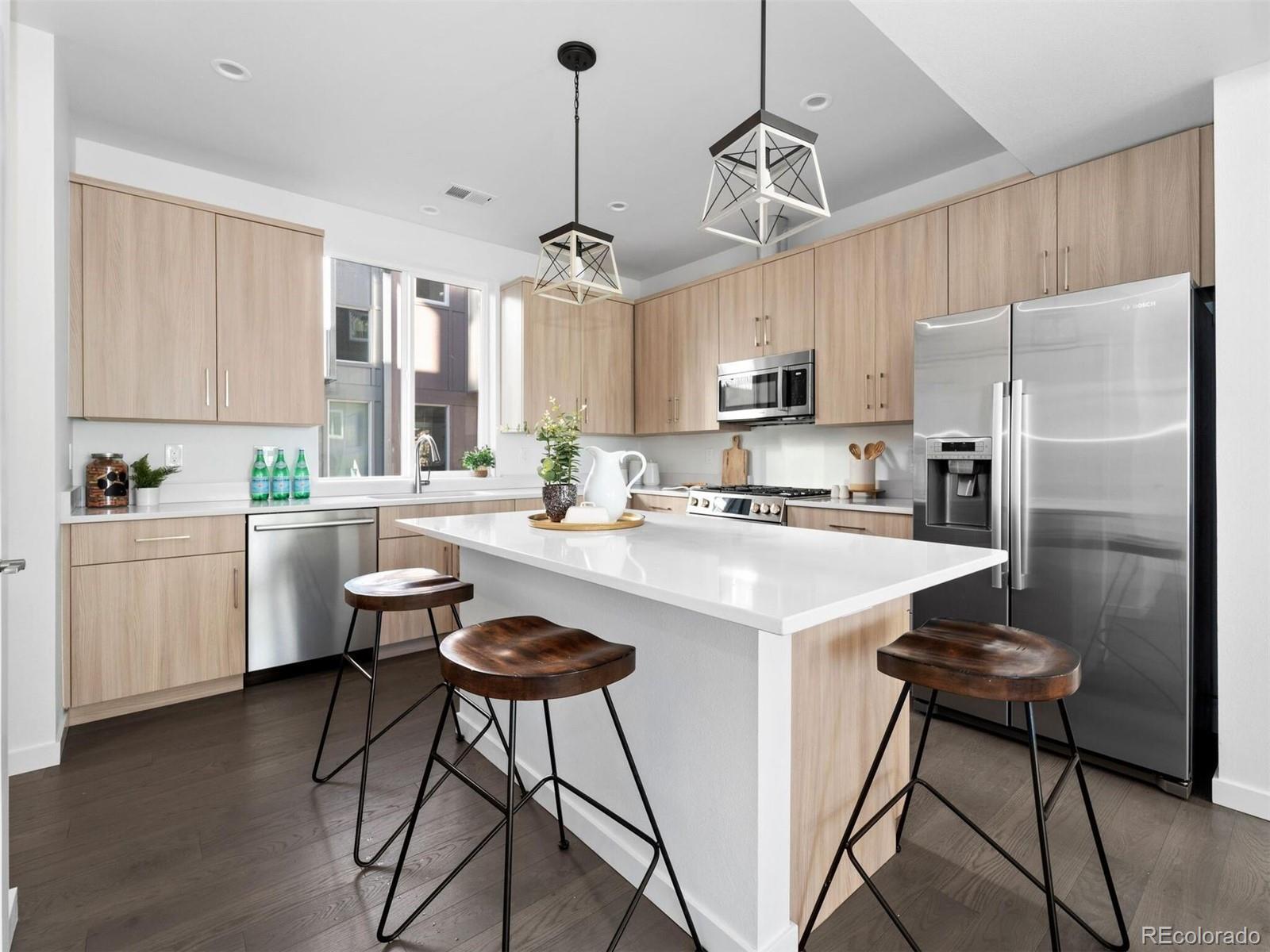 a kitchen with stainless steel appliances granite countertop a refrigerator a sink dishwasher a stove a microwave oven a refrigerator with white cabinets and wooden floor