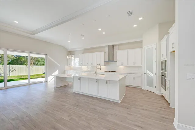 a large white kitchen with wooden floor and a large window