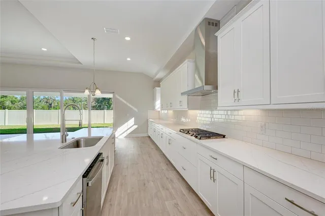 a kitchen with stainless steel appliances granite countertop a sink and white cabinets