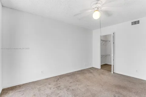 a view of an empty room with a chandelier fan