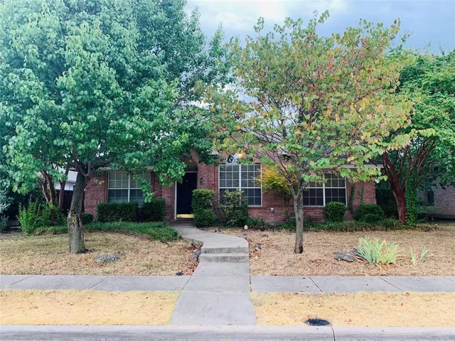 a front view of a house with a yard and potted plants