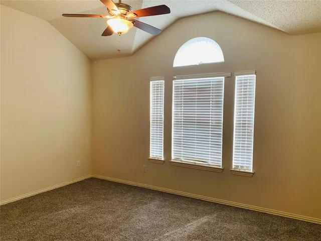 an empty room with chandelier fan and windows