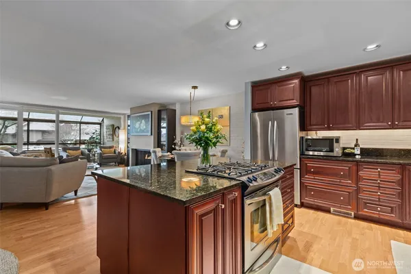 a kitchen with kitchen island granite countertop a stove refrigerator and cabinets