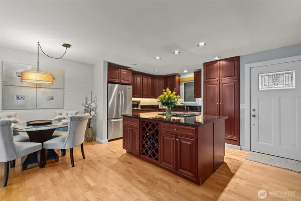 a kitchen with stainless steel appliances kitchen island granite countertop a table and chairs in it