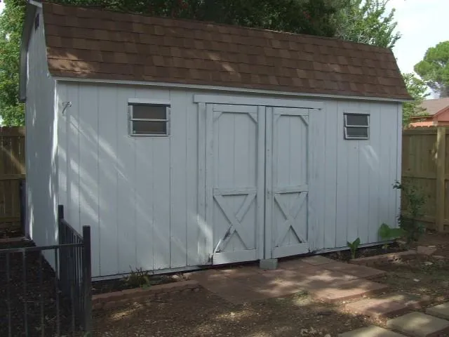a view of a backyard with large tree and wooden fence