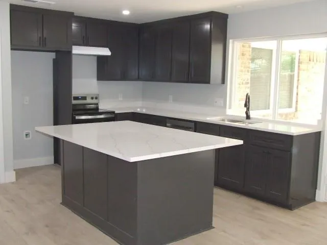 a kitchen with stainless steel appliances a sink a stove a refrigerator and cabinets