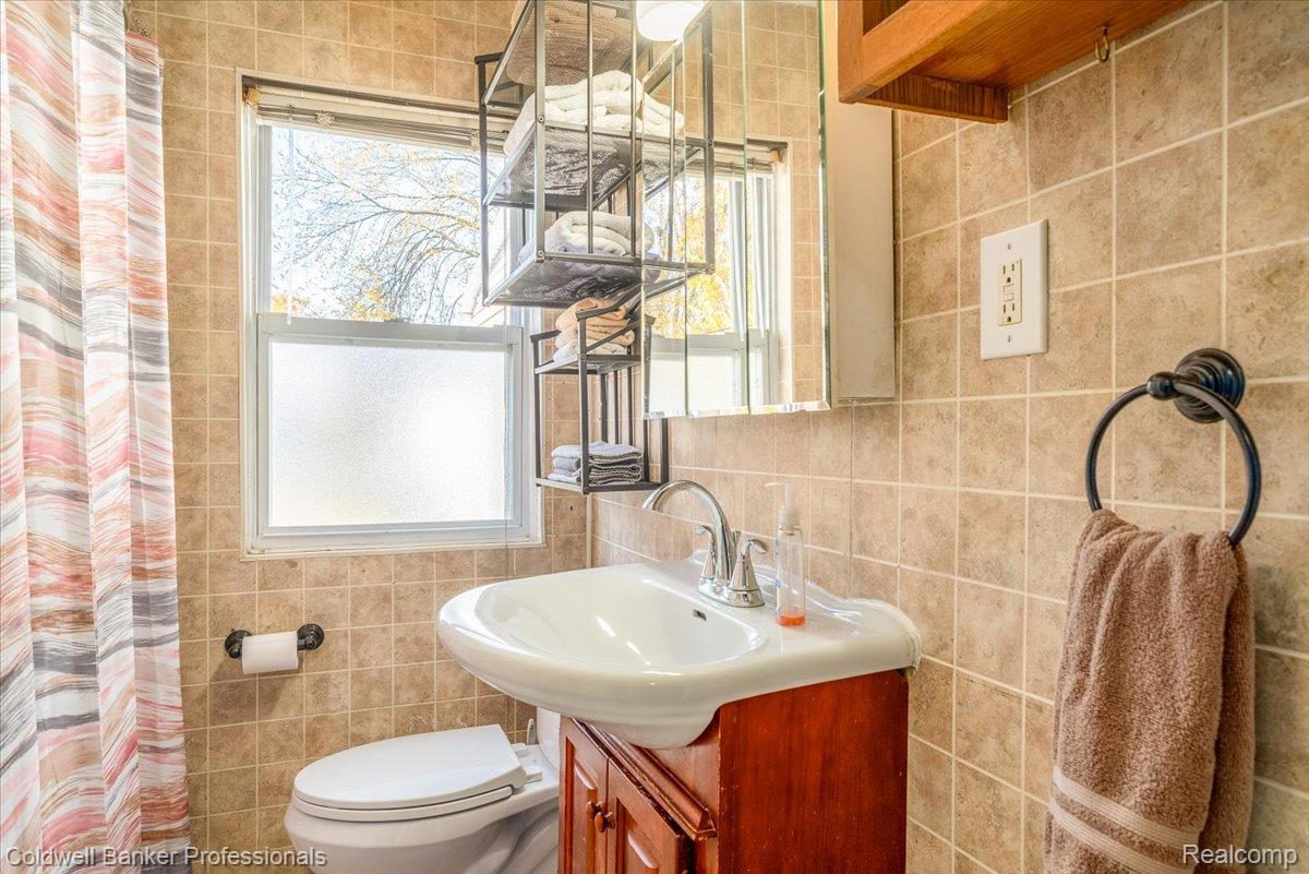 3582 Swanson Street Wayne, MI 48184 - Photo 20 of 30 Full bathroom with tile walls, vanity, healthy amount of natural light, a shower with curtain, and tasteful backsplash