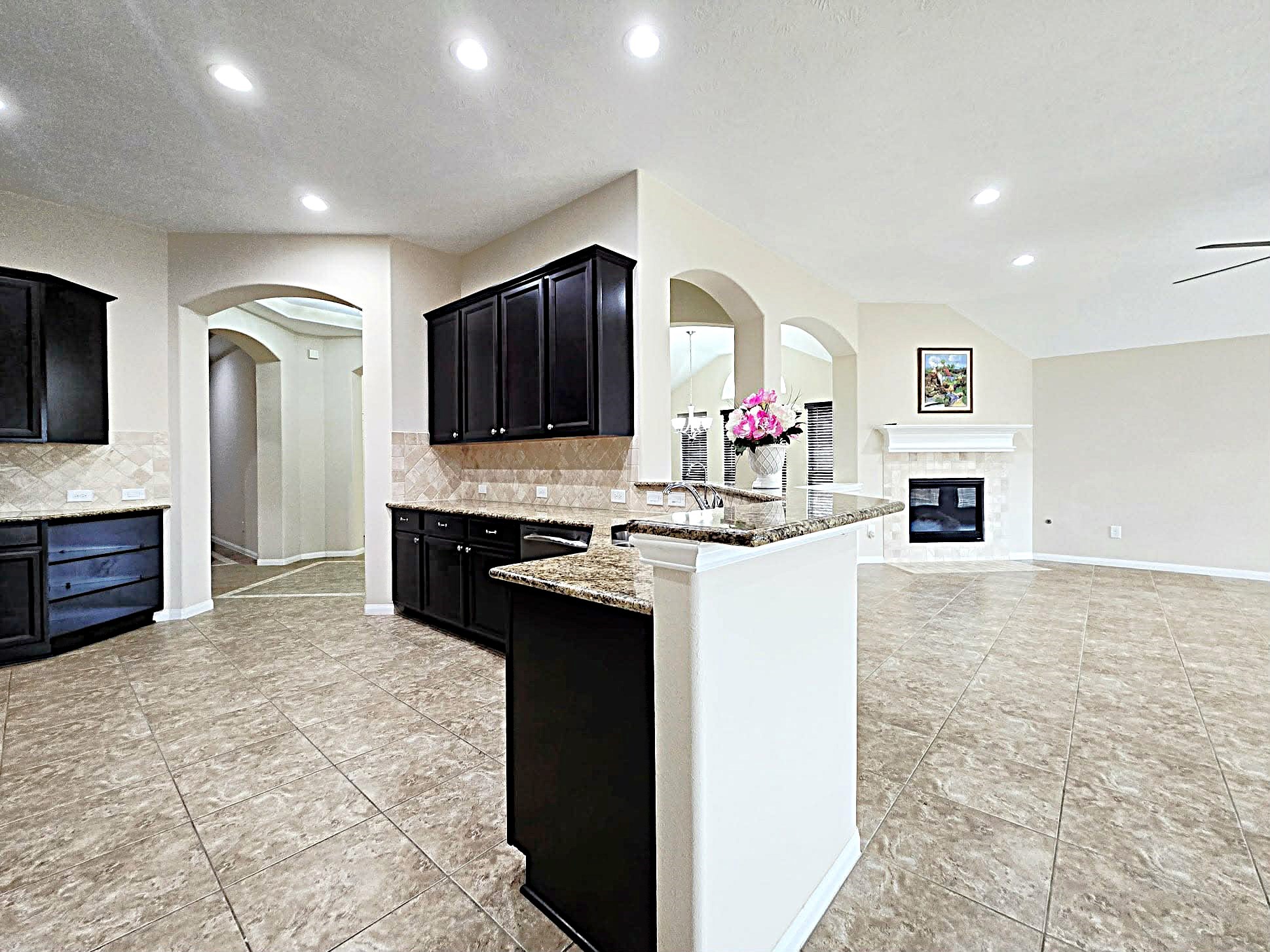 14015 Hailey Springs Lane Humble, TX 77396 - Photo 22 of 34 a kitchen with kitchen island granite countertop a stove top oven a sink dishwasher a refrigerator and a fireplace with wooden floor