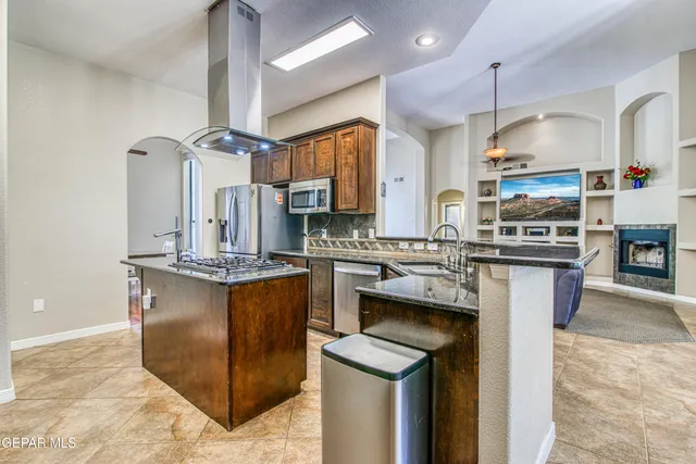 a kitchen with stainless steel appliances granite countertop a stove a sink dishwasher and cabinets with wooden floor