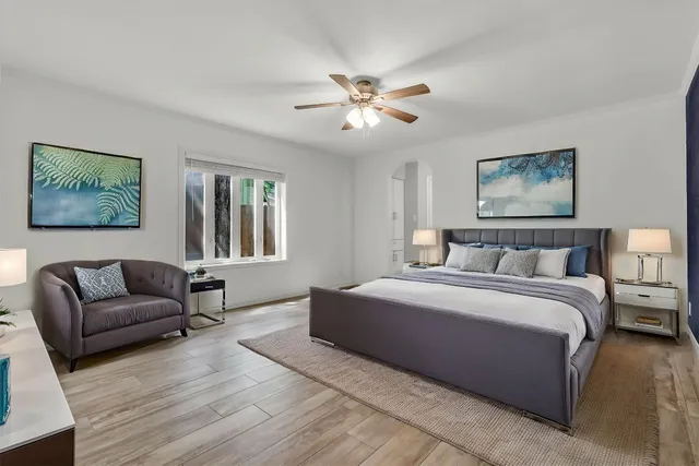 a spacious bedroom with a large bed couch and two windows