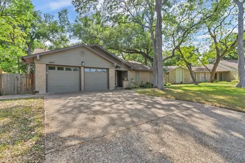 a view of a house with a yard and large tree