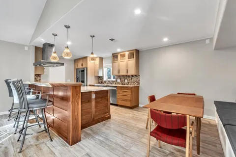 a kitchen with stainless steel appliances kitchen island granite countertop a table chairs stove and white cabinets