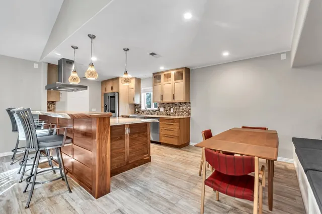 a kitchen with stainless steel appliances kitchen island granite countertop a table chairs stove and white cabinets