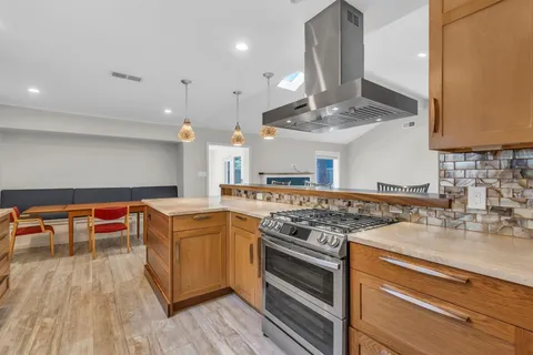 a kitchen with stainless steel appliances granite countertop a stove and a wooden floors