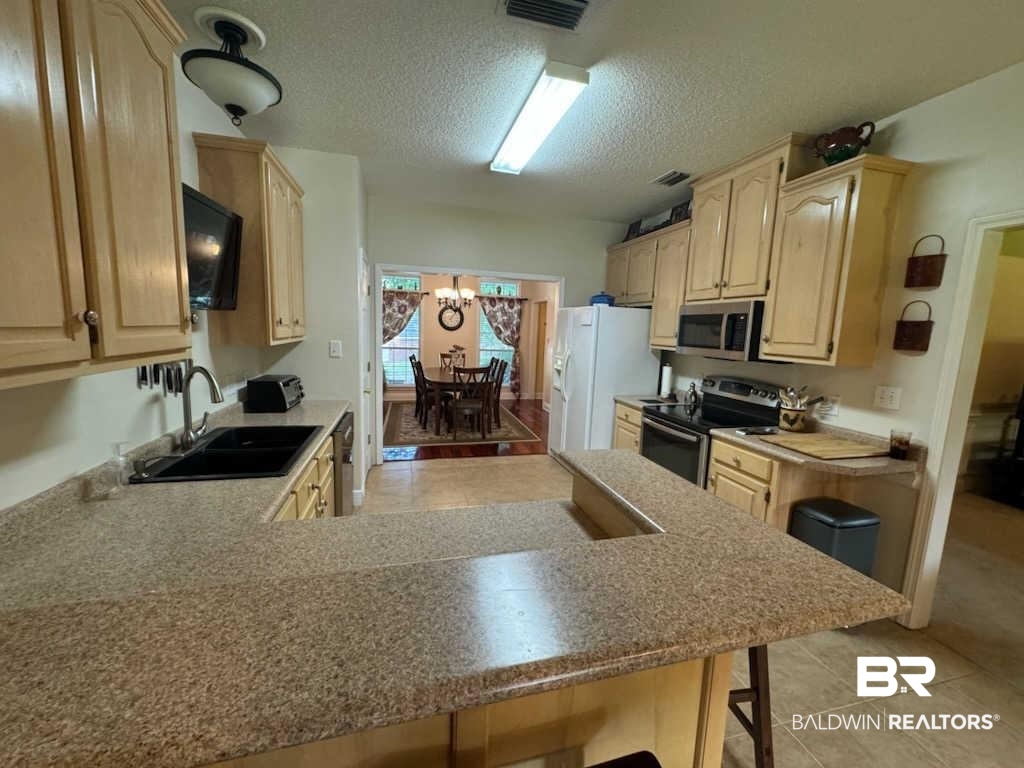 31163 Woodland Way Daphne, AL 36527 - Photo 19 of 44 Kitchen featuring sink, an inviting chandelier, light tile patterned floors, stainless steel appliances, and kitchen peninsula
