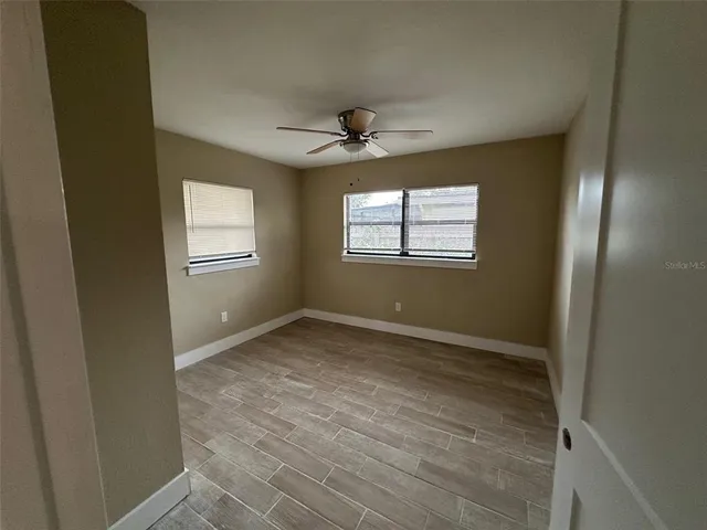 an empty room with windows and fan