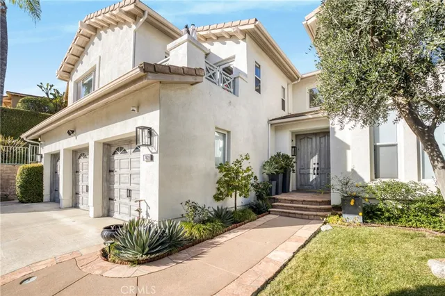 a view of a house with brick walls plants and large tree