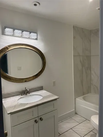 a bathroom with a granite countertop sink a toilet and bathtub