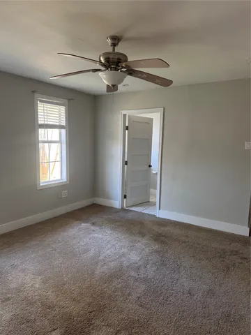 an empty room with windows and fan