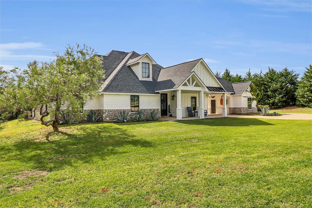 Modern farmhouse exterior with white siding, stone accents, and a dark roof