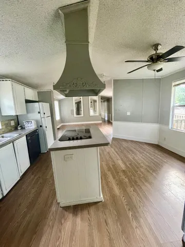 a kitchen with stainless steel appliances a stove a sink a refrigerator white cabinets and wooden floor