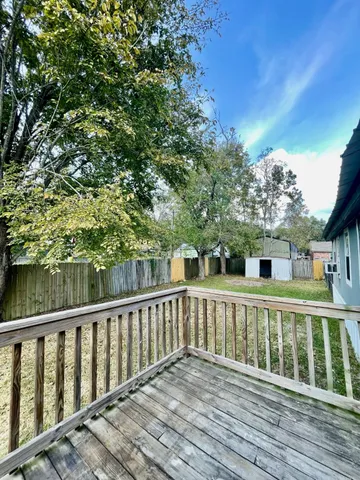 a view of a wooden deck and a yard with swimming pool