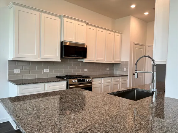 a kitchen with stainless steel appliances granite countertop a stove a sink and a microwave