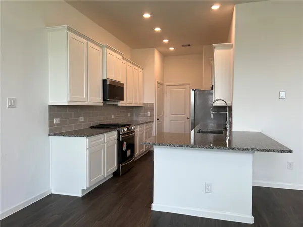 a kitchen with granite countertop a stove top oven and sink