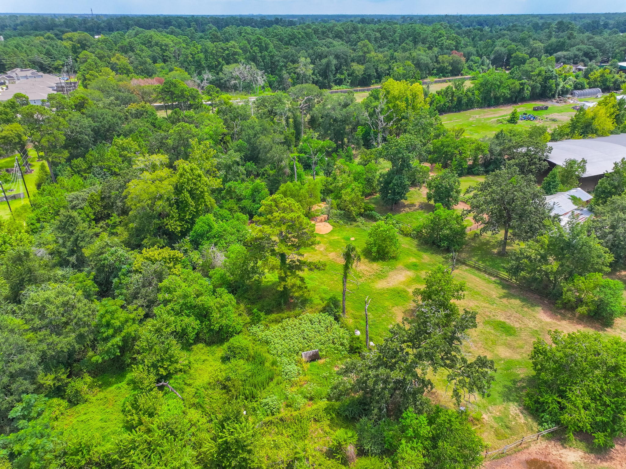 25635 Hufsmith Cemetery Road Tomball, TX 77375 - Photo 27 of 50 This aerial view reveals the natural topography and excellent usability of this well-situated Tomball acreage — clear open fields with established tree lines, functional existing structures, and road access that makes this a property ready to be put to productive use from practically day one of the new owner taking possession of the land.