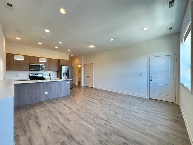 a large kitchen with stainless steel appliances a large counter top a stove a sink and a refrigerator